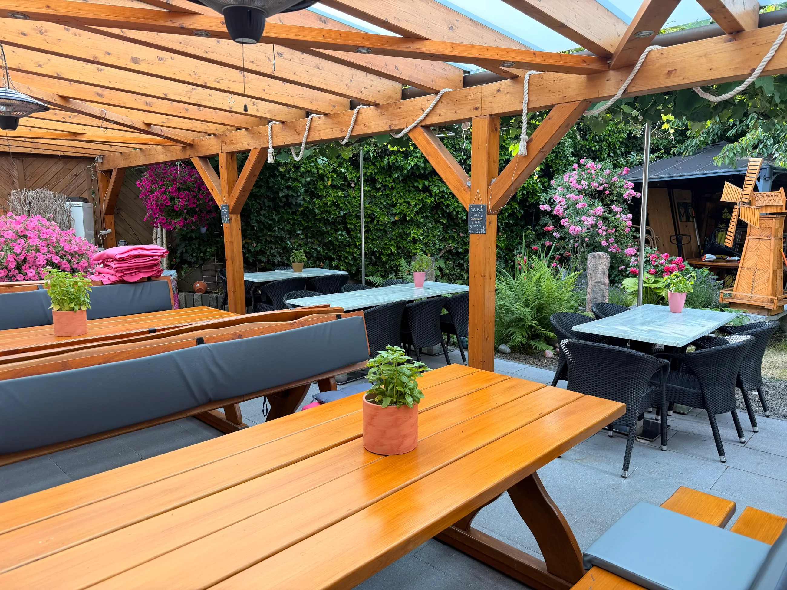 Überdachter Biergarten mit Holztischen und Blumen — Gasthaus Großenohl in Gummersbach-Derschlag